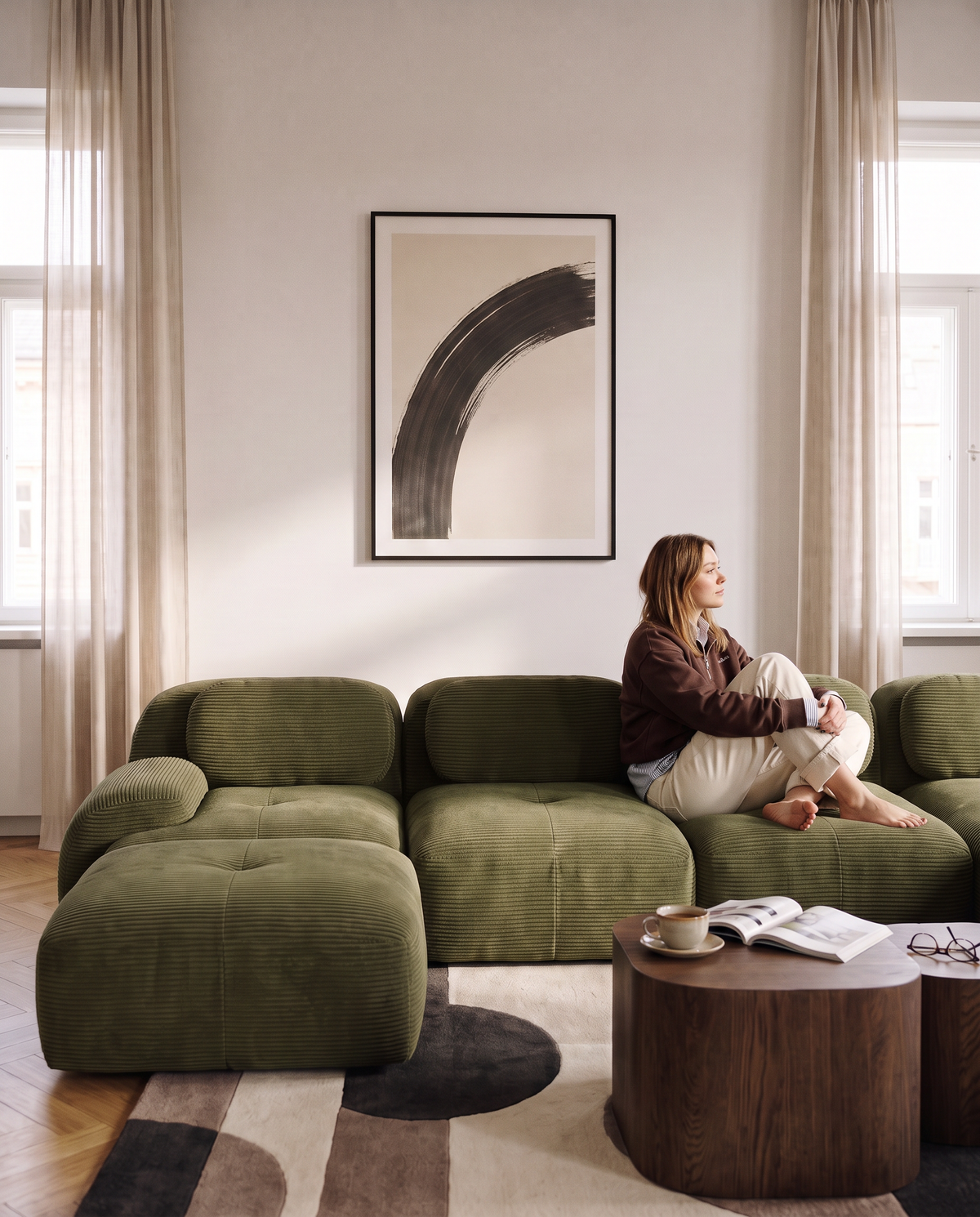 Canapé compressé en U Archipel en velours côtelé vert, femme assise dans un salon lumineux