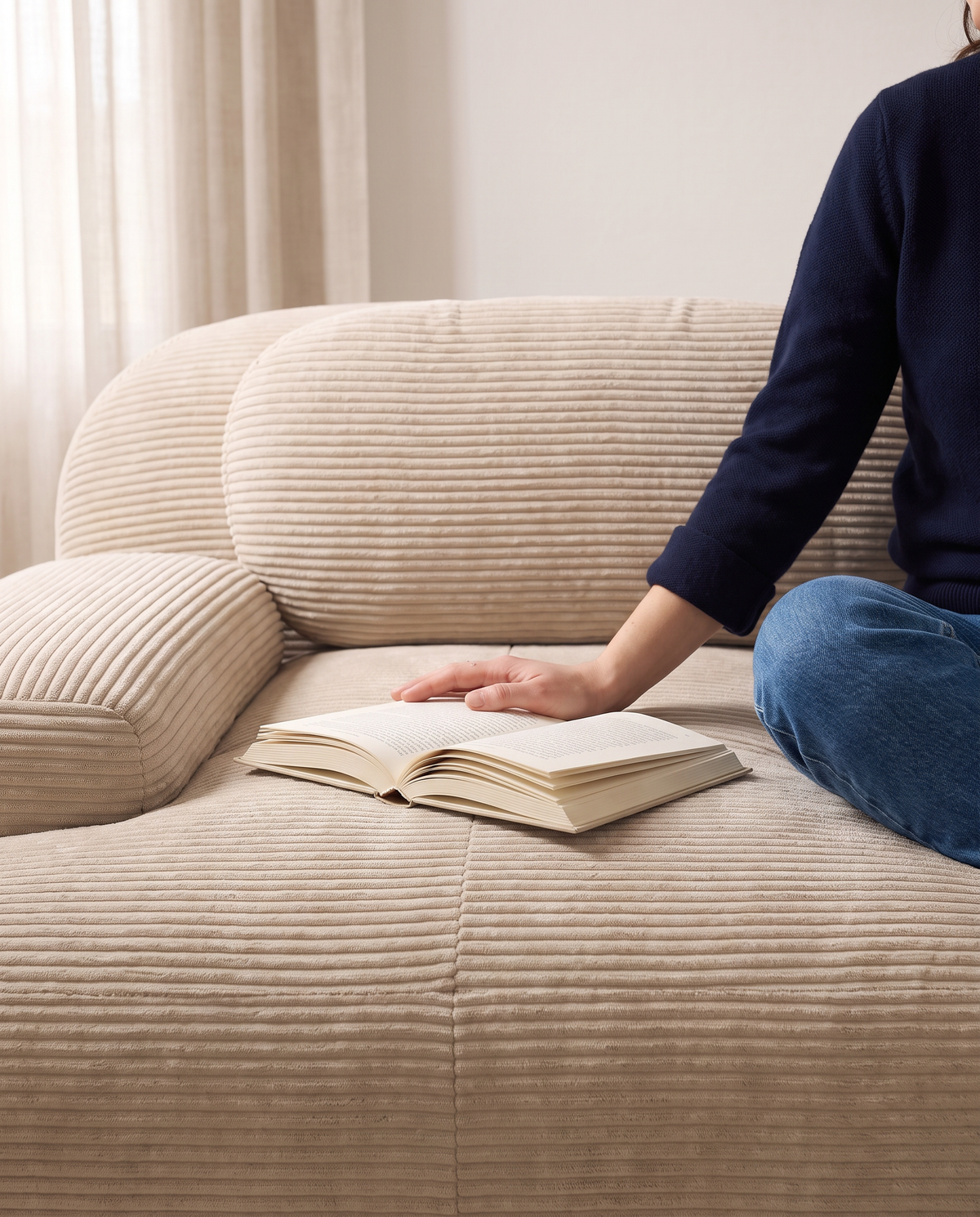 Détail de l'assise du canapé Crique, une personne assise feuillette un magazine