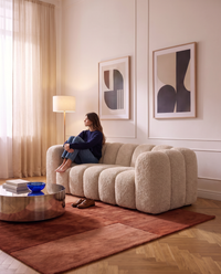 Canapé compressé 3 places Dune en bouclette beige, femme assise dans un salon lumineux